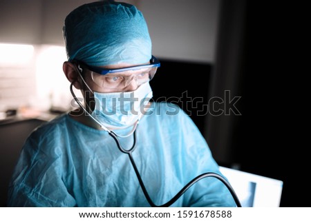 Doctor male surgeon in uniform working with a stethoscope in a medical office.