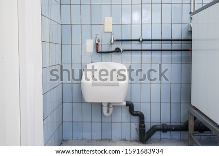 in an public restroom hangs on an wall of an white sink