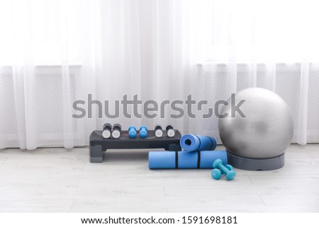 Different sports equipment near window in gym. Space for text
