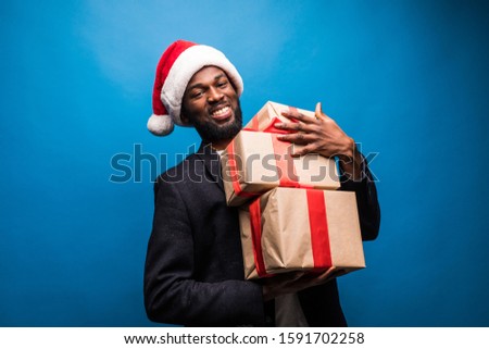 Young African American man wearing a santa hat offering a gifts
