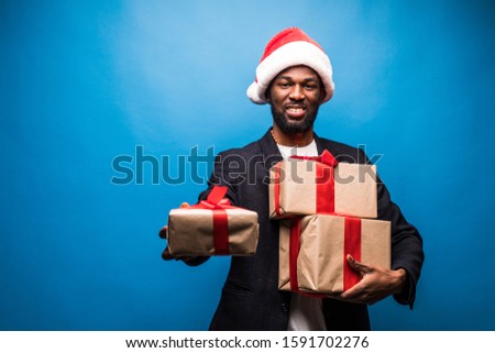 Young African American man wearing a santa hat offering a gifts