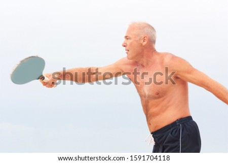 Adult male playing matkot on the beach