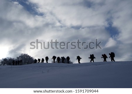 Ski hiking in cloudy day. Ski mountaineering people moving on a snowy surface. Winter view in a sunny day.