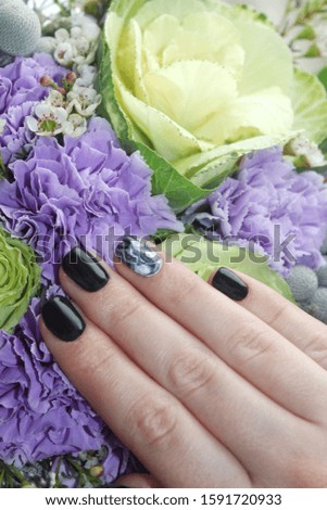 Stylish fashionable woman's manicure. Black nails on colored flowers. Nail polish. Artistic manicure. Modern style. Spring manicure.