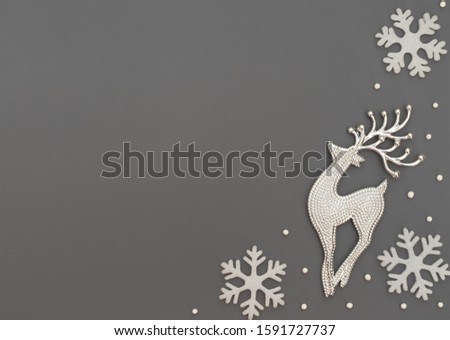 Christmas or winter grey background with one deer and white snowflakes and beads. New Year greeting card. Christmas, New Year or winter concept. Flat lay style with copy space.
