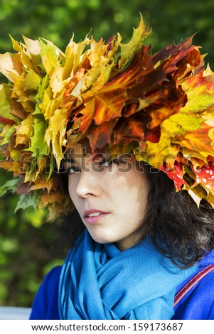 Woman with maple leaves on head look suspiciously