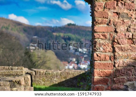 Wall of old castle ruin called 'Hinterburg' in city Neckarsteinach in Germany with blurry 'Odenwald' forest in background