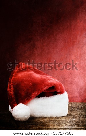 Textured image of a Santa Hat over a rustic wooden background with room for text.