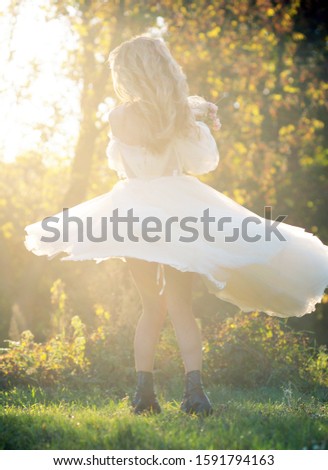 Happy bride in a white wedding dress swirls in the autumn forest on a sunny and warm day.Beautiful happy bride dancing and spinning in the park in her wedding day.