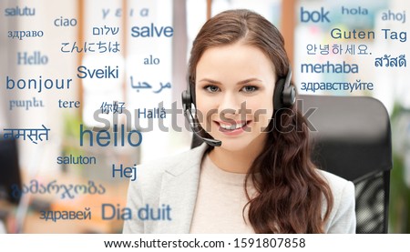 business and technology concept - smiling female translator or operator in headset at office with greeting words in different foreign languages