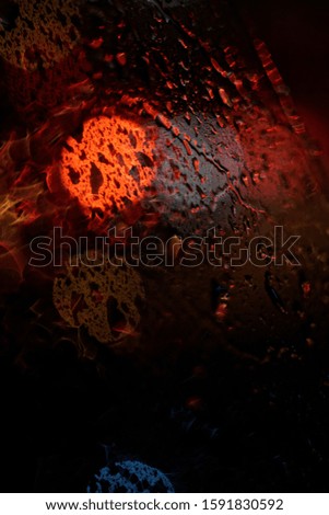 Close up rain drops on window with red road light bokeh and dark blackground