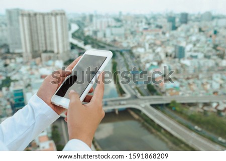 Woman uses Mobile Phone at cityscape background in morning light, close up