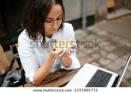 Beautiful brunette using laptop in cafe. Portrait of young smiling businesswoman having a break.