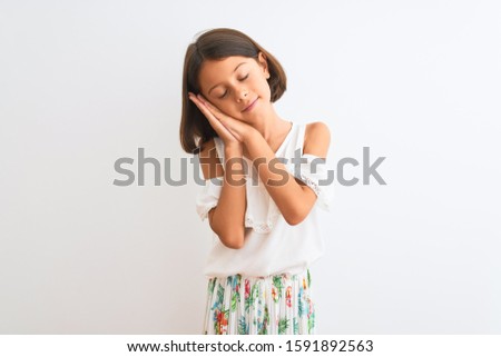 Young beautiful child girl wearing casual dress standing over isolated white background sleeping tired dreaming and posing with hands together while smiling with closed eyes.