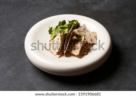 Guacamole with pita chips on white plate. Chef's signature dish, luxury gastro cafe menu food on dark background with copy space. Mexican guacamole dish.