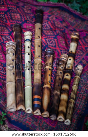 Shakuhachi flute. Hand made from bamboo root. Japanese folk tradition. Musical instrument of a samurai. For meditation and prayer to Zen monks. Lies on a stone. Color in dark and light colors.