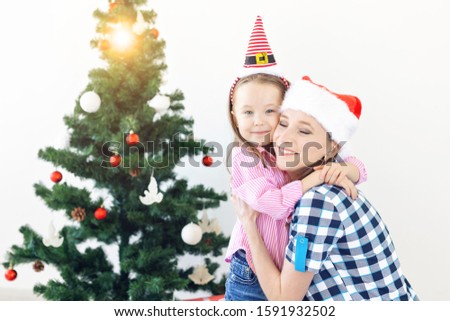 Christmas, family and holidays concept - Festive mother and daughter on the couch at home in the living room