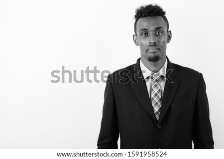 Young bearded African businessman wearing suit against white background