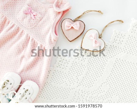 New born postcard or greeting card. Baby girl dress, baby booties and two heart. Decorative Knit. Copy space. Flat bunk. View from the top. 