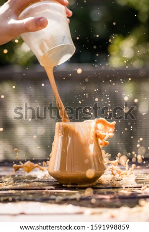 Picture of a person rapidly pouring cold brew in a glass creating a splash