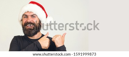 Handsome guy advertising something and looking at camera. Attractive man in santa hat showing blank copy space christmas product, present, gift, greeting and wishes text.