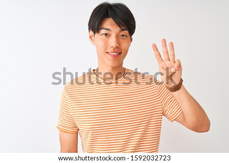 Young chinese man wearing casual striped t-shirt standing over isolated white background showing and pointing up with fingers number three while smiling confident and happy.
