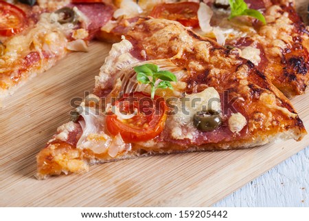 Pizza with salami, tomatoes and olives on table 