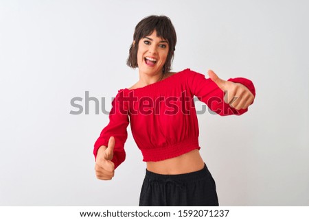 Young beautiful woman wearing red summer t-shirt standing over isolated white background approving doing positive gesture with hand, thumbs up smiling and happy for success. Winner gesture.