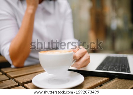 Woman sitting at cafe with laptop. Female  hand on laptop and cup of coffee.