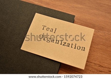 The word "TEAL ORGANIZATION" stamped on sticky note with a notebook in diagonal angle.