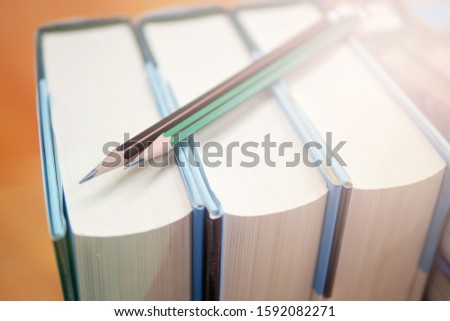 Stack of books with pencils on top, selective focused picture of education concept, literature books on a shelf in a library or the study room in school, vocational institute, college, or university