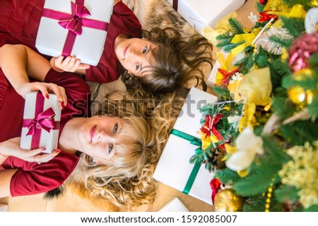 Mom with a daughter near the Christmas tree with gifts. Selective focus.