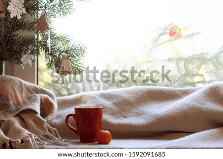 red mug, plaid green Christmas tree with decorations in front of the window on a festive day. cozy home coffee break