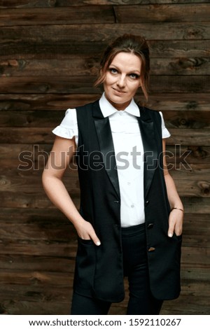 Portrait of an adult pretty woman 40 years old in a business suit on a background of wood. Business concept. Standing right in front of the camera with a serious mood.