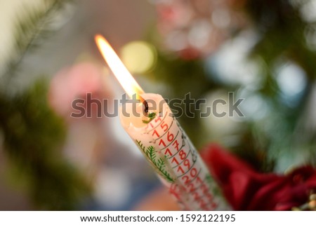 Countdown to Christmas holiday on burning candle with calendar of days of December