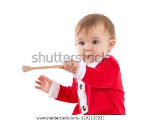 Stock studio photo with a white background of a baby dressed as Santa Claus moving a wooden stick