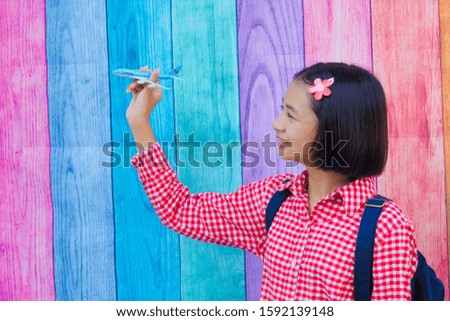 Happy young asia girl hold plane and smile with colorful background.