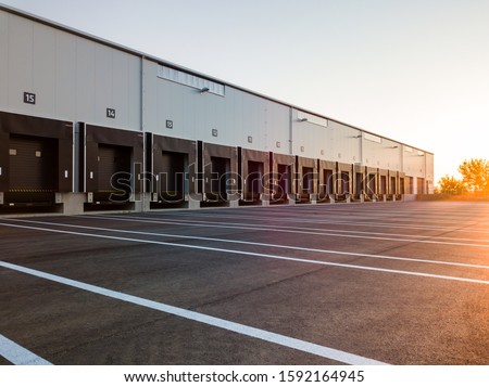 Warehouse exterior with loading ramps and slots for trucks to park - modern industry warehouse storage building. Royalty-Free Stock Photo #1592164945