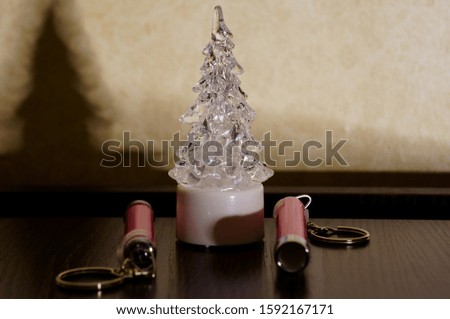 Photo of a pink keychain and a Christmas tree on a dark background. Subjects close up.