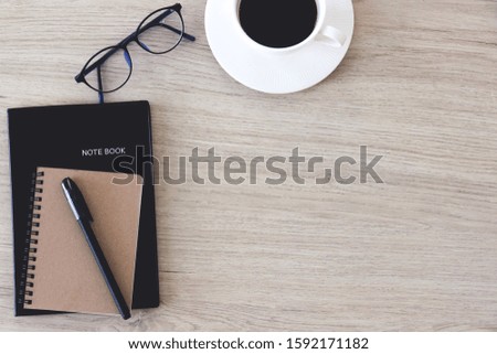 Notebooks and pen for writing with glasses and cup of coffee on wooden desk office, top view, with copy space.
