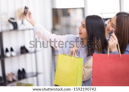 Two beautiful Asian women are shopping in the mall. And take pictures with the phone
