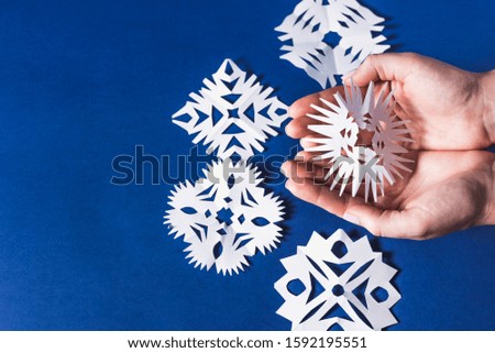 background of various Christmas themed snowflakes cut out of white paper on a trendy blue background 2020