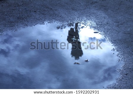 The Reflection Of The Sky And A Streetlight In A Puddle Of The Street