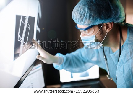 male surgeon orthopedic traumatologist touches a touch screen with a x-ray of the bone.