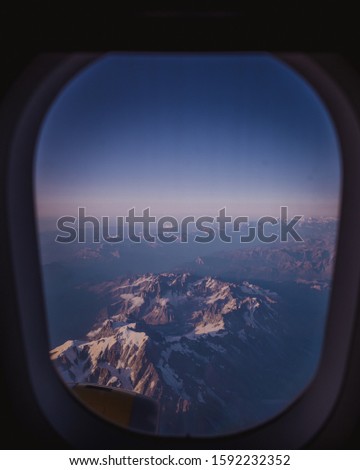 Picture taken on board an aircraft with a view of the window and the snow-covered mountains of the Alps