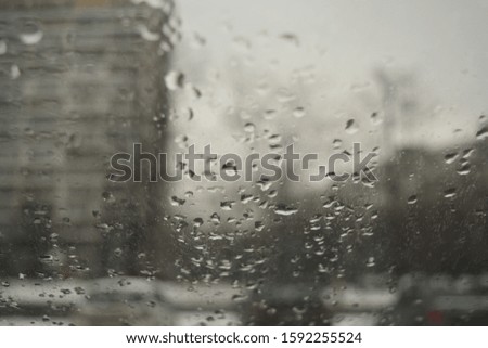 View of the street through the misted glass with drops of water. Day, cars, houses.