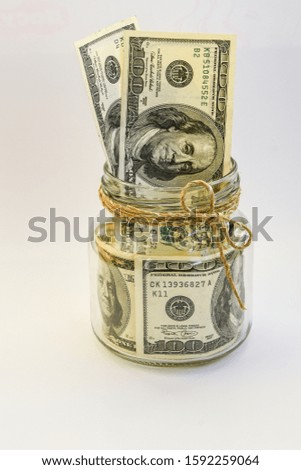 one hundred american dollars in the jar on the white backround with copy space, savings, Many 100 US dollars bank notes in a glass jar