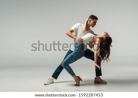 dancers in denim jeans dancing bachata on grey background Royalty-Free Stock Photo #1592287453