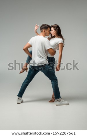 dancers in t-shirts and jeans dancing bachata on grey background Royalty-Free Stock Photo #1592287561