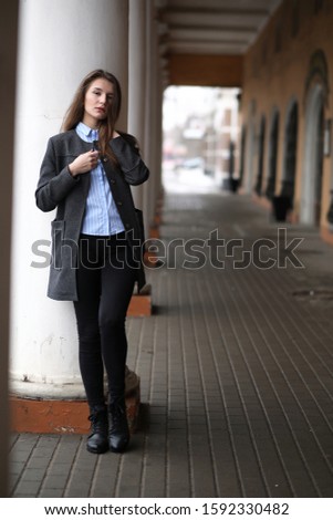 Young beautiful girl on a walk near a building with a column
